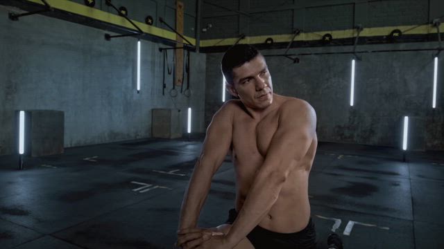 A shirtless muscular man prepares for her fitness routine by warming up with lunges before his training.